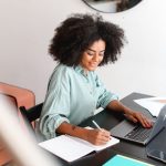 A happy woman working on a computer from her home office.