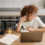 A happy, confident woman working from home on a laptop in her kitchen.