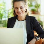 A woman using a laptop at home to search for remote jobs on a staffing agency website.