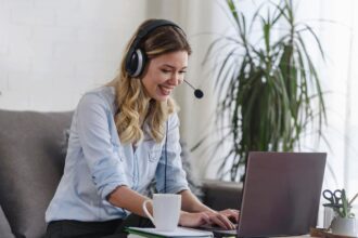 An American Express remote customer service agent working from home and taking calls from her laptop, sitting on the couch.