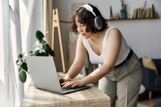 A woman working from home on her laptop reading a review on Apple work from home jobs