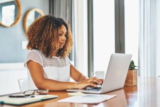 A woman searching for jobs on a laptop in her home office.