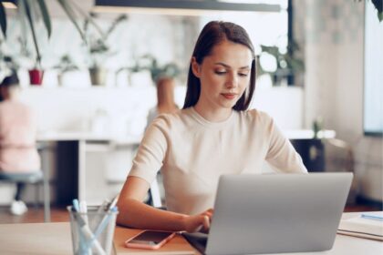 A woman sitting at a table working in a cafe on her laptop.