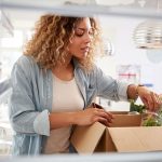 A busy mom sorting and putting away groceries from a boxed meal planning service.